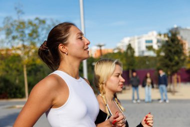 İki arkadaş spor kıyafetlerinde yan yana koşuyor, enerjilerini ve motivasyonlarını paylaşıyorlar..