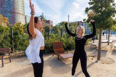 İki kadın direniş eğitimi için bantları kullanıyor. Parkta denge ve güç üzerine çalışıyorlar..