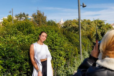 İki arkadaş, parkta yürürken, neşeli ve rahat bir açık hava sahnesinin tadını çıkarırken, eski bir kamerayla eğlenceli anları yakalıyorlar..