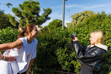 İki arkadaş eski bir kamerayla eski tarz selfie çekerken parkta dostça bir gezinti yapıyorlar..