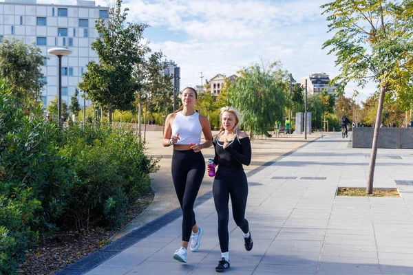 İki kadın spor salonunda yan yana koşuyor, temiz havanın ve hareketin tadını çıkarıyorlar..