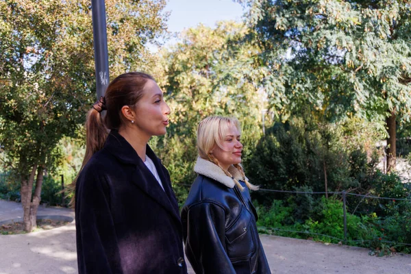 Parlak bir parkta yan yana yürüyen iki kadın, sessiz ve keyifli bir açık hava anının tadını çıkarırken arkadaşça sohbet ediyorlar..