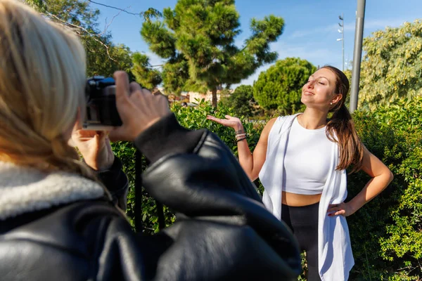 İki arkadaş poz vermek ve klasik bir kamerayla fotoğraf çekmek için durur. Parkta huzurlu ve aydınlık bir yürüyüşün tadını çıkarırlar..