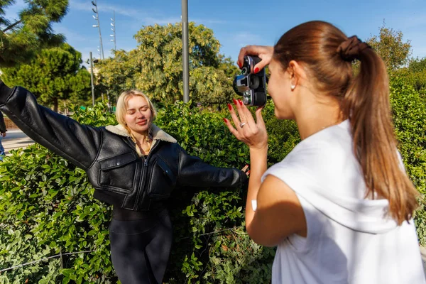 İki arkadaş, parkta yürürken klasik bir kamera kullanarak doğal ve sakin bir ortamın keyfini çıkarırken birbirlerini yakalıyorlar..