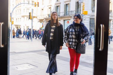 Anne ve kızı, sakin bir öğleden sonra gezintisi sırasında eski şehir sokaklarında sohbet edip vitrinlere hayran bakıyorlar.