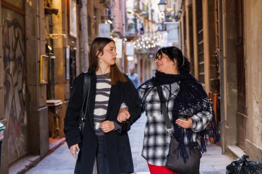 Klasik eski caddelerde rahatça yürürken anne kız sohbet ediyor ve geçtikleri dükkanlara hayran kalıyorlar..