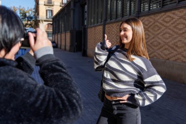 Anne ve kızının canlı şehir alanlarında yürürken fotoğraflarını çektikleri samimi bir an.