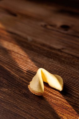 Kırsal bir ahşap yüzeyde otantik şans kurabiyeleri. Karanlık ortam bu geleneksel doğulu kutlama atıştırmalıklarının altın dokusunu vurguluyor..