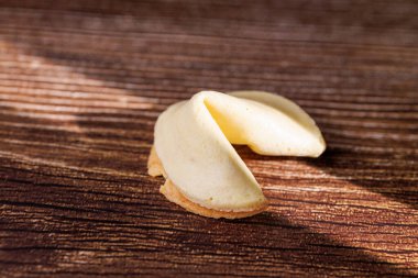 Karanlık bir ahşap yüzeyde otantik altın talih kurabiyeleri. Bu ikonik muamele, tüm dünyada kaderi ve bayram kutlamalarını temsil etmek için mükemmeldir..