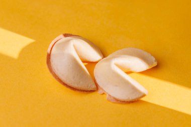 Parlak sarı bir yüzey üzerinde geleneksel Çin şans kurabiyeleri. Keskin ışık oyunu, pazarlama için bu ikonik atıştırmalıkların dokusunu vurgular.!!