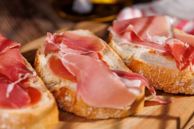 Lezzetli Akdeniz diyeti. İçinde İber jambonu ve köy tahtasında zeytin yağı var. Koyu arkaplan gurme markalaşması için zarif bir dokunuş ekler.