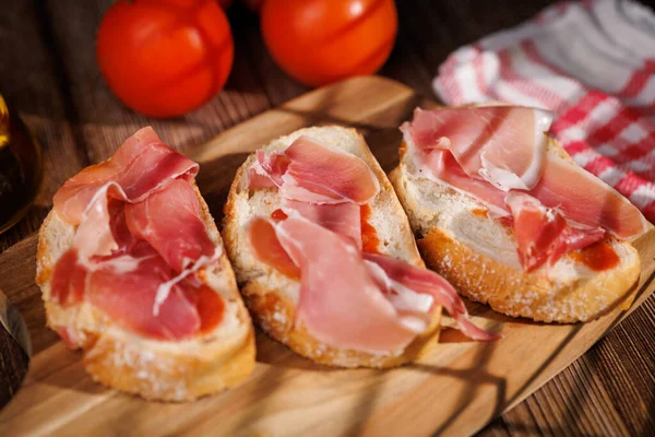 Hakiki İspanyol aperatifi. Köy tahtasında pişirilmiş jambon ve zeytinyağı. 2026 'da geleneksel yemekleri ve sağlıklı yaşam tarzını temsil etmek için mükemmel..