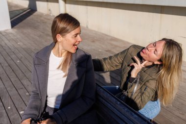 En iyi arkadaşlar iskelede bir anı paylaşır. Mutlu bir şekilde sohbet ediyorlar, temiz havanın ve huzurlu liman ortamının tadını çıkarmak için rutinlerine ara veriyorlar..