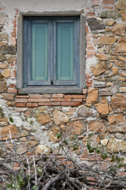 İtalya 'nın Toskana kırsalındaki terk edilmiş ve harap olmuş taş evin penceresi.
