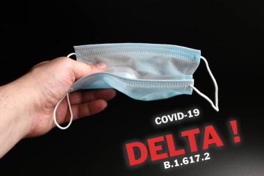Coronavirus 'a karşı korunmak için bir antiviral tıbbi maske erkek elinde. Coronavirüs' ün bir türü olan Covid-19 Delta B.1.617.2 uyarısı var..