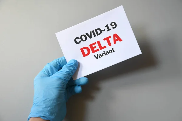 Doctor\'s hand in blue glove with white paper and text Covid-19 Delta Variant. Concept of medical variety delta variant and COVID-19. Concept words \'delta variant\'. COVID-19 delta variant concept.