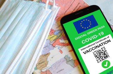 Akıllı telefonun ekranında QR kodu olan Avrupa Birliği 'nin dijital yeşil geçiş kartı. Avrupa haritası ve maskesi olan Covid veya Coronavirus aşı sertifikası