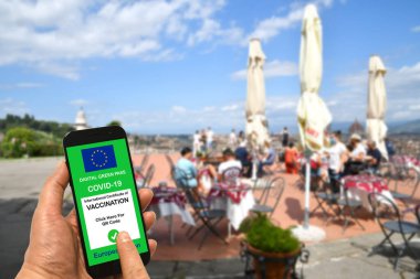 Un uomo presso un bar ristorante all 'aperte tiene in mano uno smartphone con il pass verde digitale dell' Unione europea per Covid-19. Concetto di sicurezza per Coronavirus ve Green Pass