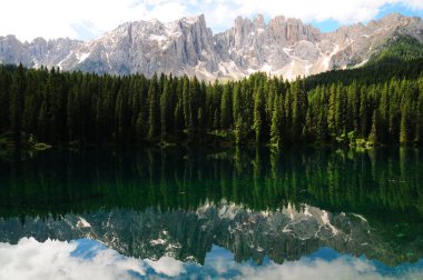 Lake Carezza. It is a small alpine lake located in the upper Val d'Ega in the municipality of Nova Levante, nestled among dense fir forests, beneath the slopes of the Latemar massif. Bolzano, Italy.