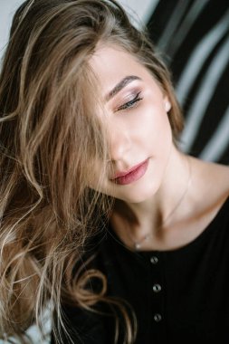 Siyah tişörtlü, sarışın, uzun saçlı güzel bir kızın portresi.