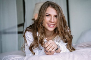 Güzel sarışın kız yatak odasında yatakta oturuyor.