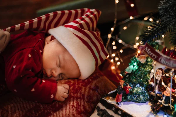 Kırmızı Noel Kostümlü Yeni Doğmuş Bebek Noel Ağacının Altında Uyuyor — Stok fotoğraf