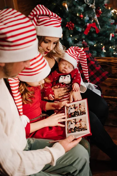 Οικογένεια Εξετάζει Τις Φωτογραφίες Στο Άλμπουμ Κοντά Στο Χριστουγεννιάτικο Δέντρο — Φωτογραφία Αρχείου