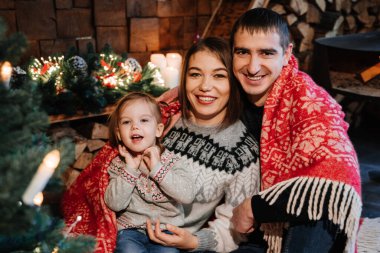 Yeni yıl ağacının yanında bir aile. Aileler kızlarına sarılırlar..