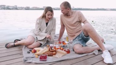 Erkek arkadaşı ve kız arkadaşı pikniğe gittiler. Göldeki tahta iskelede oturuyorlar.