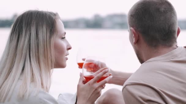 Liefdevol koppel dat wijn drinkt uit glazen aan het meer — Stockvideo