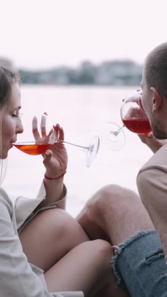 Liefdevol koppel dat wijn drinkt uit glazen aan het meer — Stockvideo