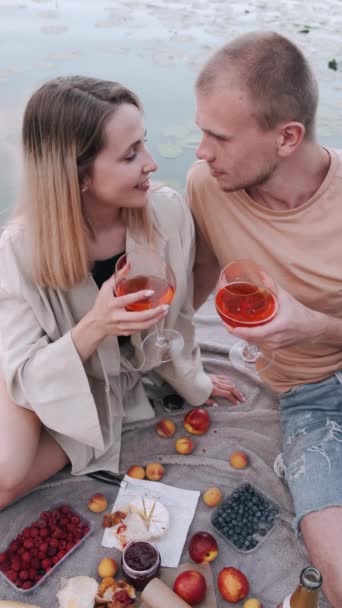 Vriend en vriendin zijn op een picknick zittend op een houten kade bij het meer — Stockvideo