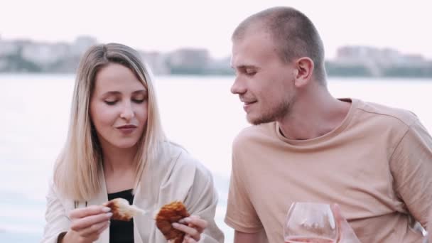 Vriend en vriendin zijn op een picknick zittend op een houten kade bij het meer — Stockvideo