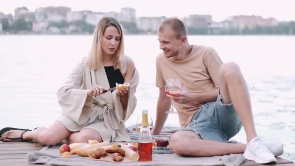 Novio y novia están en un picnic sentado en un muelle de madera en el lago — Vídeos de Stock