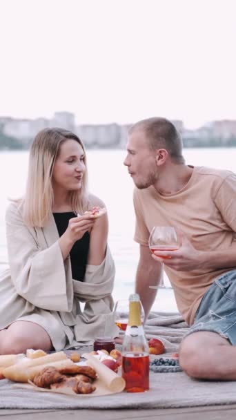Хлопець і дівчина знаходяться на пікніку, що сидить на дерев'яній набережній біля озера — стокове відео