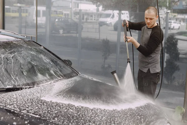 Homem bonito em uma camisola preta lavando seu carro — Fotografia de Stock