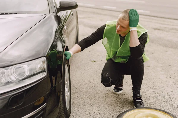 Man changing broken wheel on car