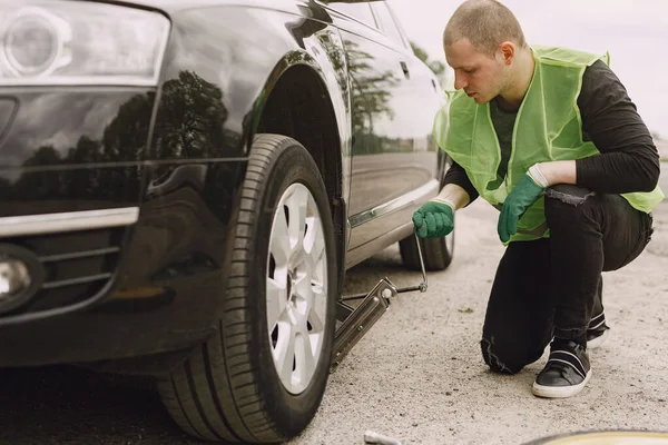 Man changing broken wheel on car