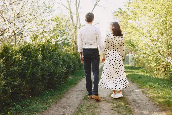 Ung man och kvinna par i en blommande trädgård — Stockfoto