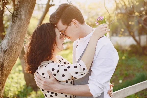 Ung man och kvinna par i en blommande trädgård — Stockfoto