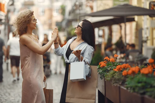 Tre eleganta kvinnor med shoppingväskor i en stad — Stockfoto