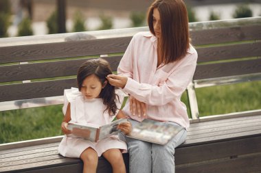 Anne ve kızı şehirde kitap okuyorlar.