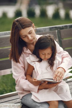 Anne ve kızı şehirde kitap okuyorlar.