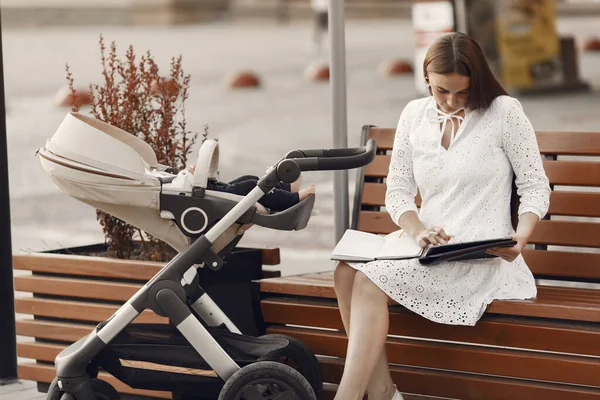 Woman in a white dress with child carriage — Stock Photo, Image