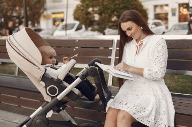 Çocuk arabası olan beyaz elbiseli bir kadın.