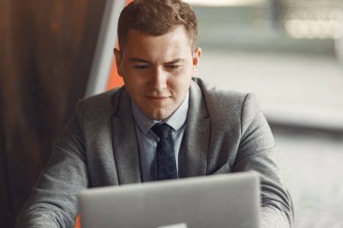 İş adamı laptopuyla kafede oturuyor.