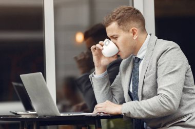 Kafede dizüstü bilgisayarlı bir iş adamı oturuyor.