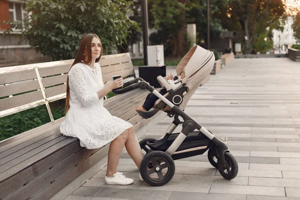 Woman in a white dress with child carriage — Stock Photo, Image