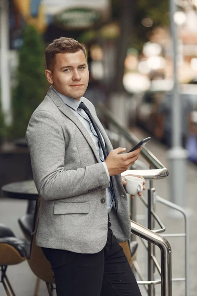 Uomo d'affari in piedi in una città con il telefono cellulare — Foto Stock