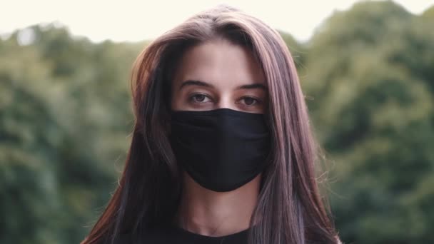 Hermosa chica pone una máscara en su cara en la naturaleza — Vídeo de stock